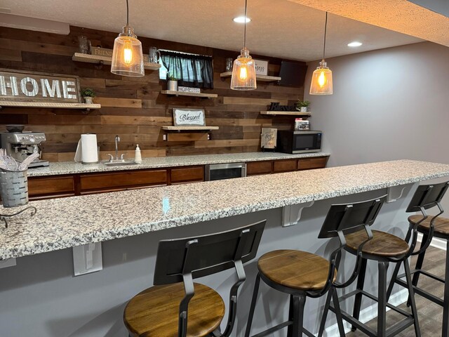 150 Shawnee Dr, Pickerington, OH 43147 - bar area with stainless steel microwave, a sink, wooden walls, decorative light fixtures, and recessed lighting