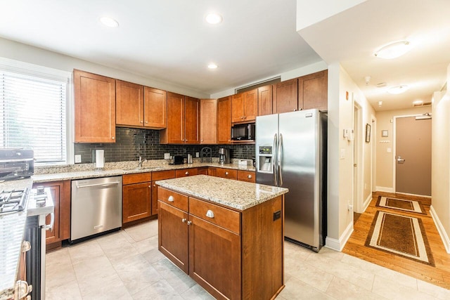 10 E Weber Rd Unit 205, Columbus, OH 43202 - kitchen featuring stainless steel appliances, decorative backsplash, light stone countertops, brown cabinets, and a center island