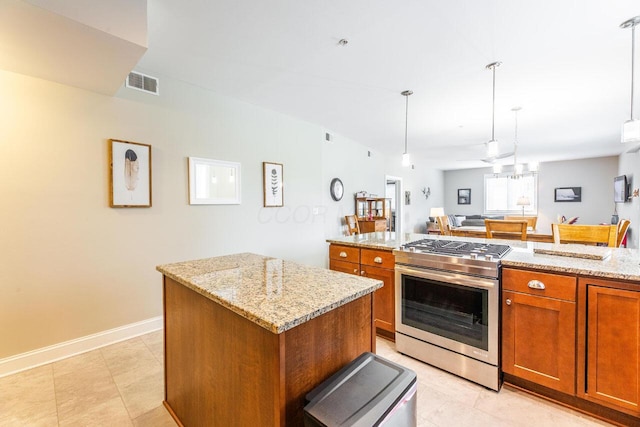 10 E Weber Rd Unit 205, Columbus, OH 43202 - kitchen featuring stainless steel gas stove, brown cabinetry, a kitchen island, light stone countertops, and decorative light fixtures