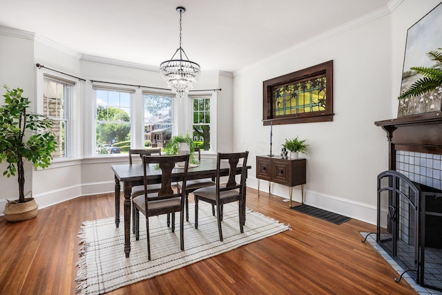 320 Rhoads Ave, Columbus, OH 43205 - dining area featuring wood finished floors, baseboards, a chandelier, ornamental molding, and a tile fireplace