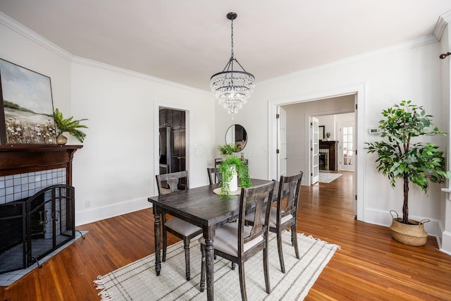 320 Rhoads Ave, Columbus, OH 43205 - dining area featuring a tiled fireplace, ornamental molding, wood finished floors, baseboards, and a chandelier