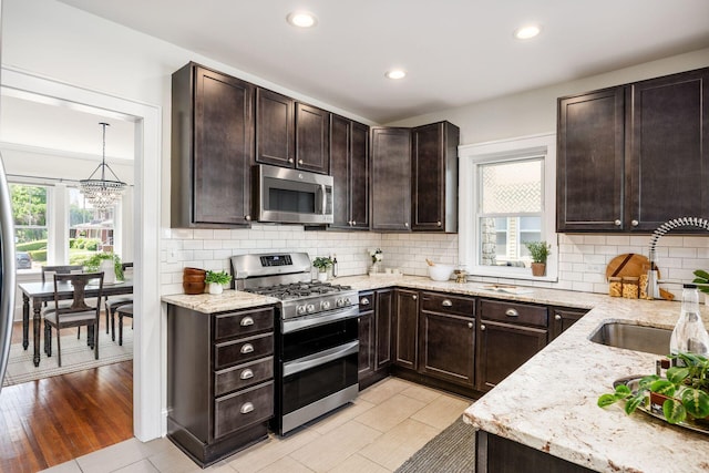 320 Rhoads Ave, Columbus, OH 43205 - kitchen with appliances with stainless steel finishes, a sink, light stone countertops, dark brown cabinets, and a chandelier