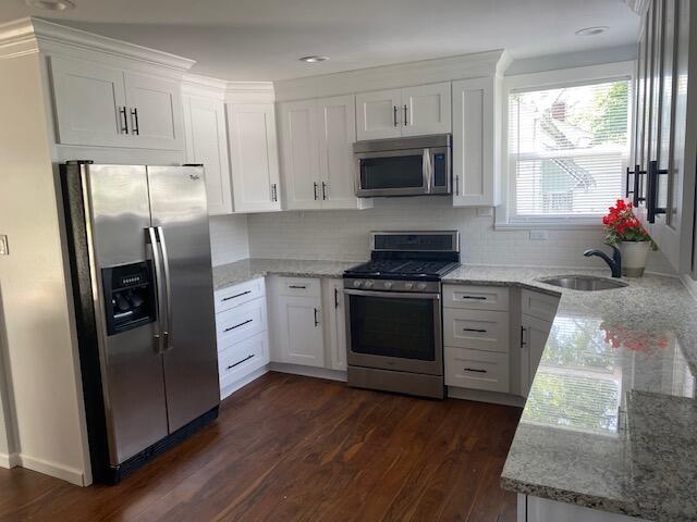 2691 Howey Rd, Columbus, OH 43211 - kitchen featuring stainless steel appliances, a sink, dark wood-style flooring, light stone counters, and white cabinets