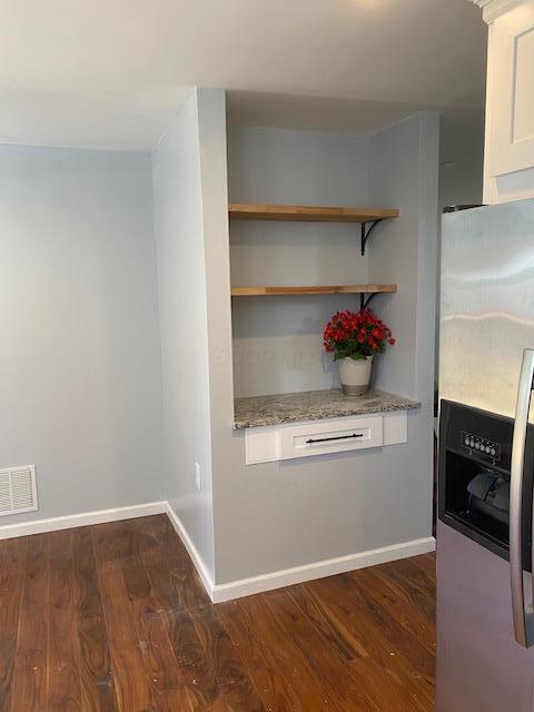 2691 Howey Rd, Columbus, OH 43211 - kitchen featuring stainless steel fridge with ice dispenser, dark wood finished floors, light stone countertops, white cabinetry, and baseboards