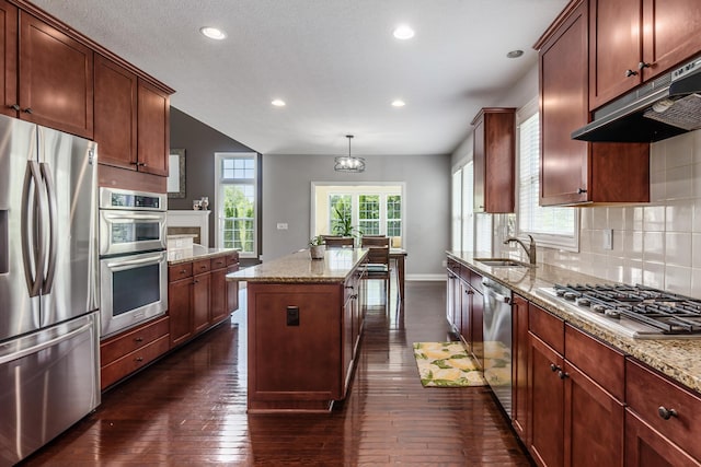 7685 Skarlocken Grn, New Albany, OH 43054 - kitchen with stainless steel appliances, under cabinet range hood, a kitchen island, dark wood-type flooring, and recessed lighting
