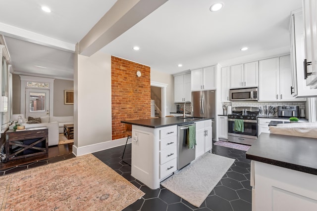 1140 Summit St, Columbus, OH 43201 - kitchen with appliances with stainless steel finishes, dark countertops, a center island with sink, recessed lighting, and white cabinetry