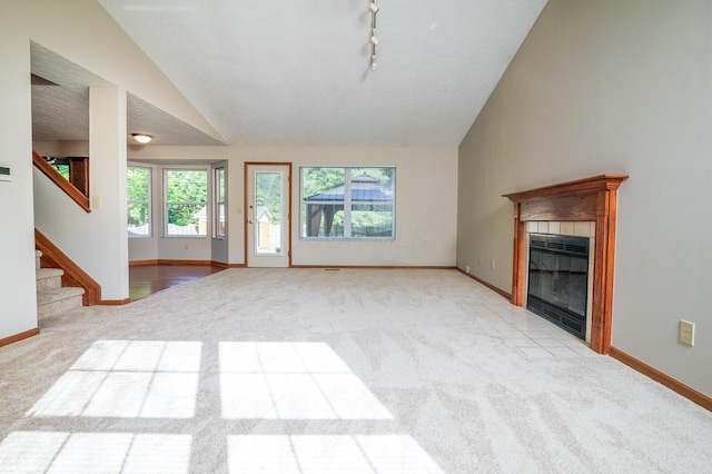 3476 Bayspirit Ct, Reynoldsburg, OH 43068 - unfurnished living room with vaulted ceiling, light carpet, a tiled fireplace, and stairs