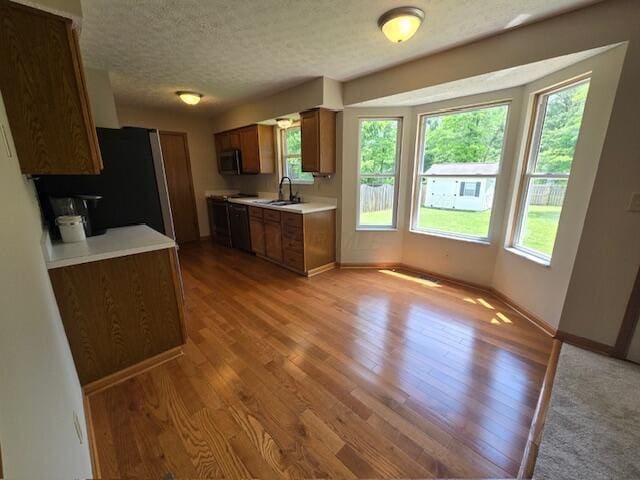 3476 Bayspirit Ct, Reynoldsburg, OH 43068 - kitchen featuring light countertops, freestanding refrigerator, light wood finished floors, brown cabinetry, and a textured ceiling
