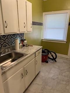 863 E Whittier St, Columbus, OH 43206 - kitchen featuring white cabinets, light countertops, a sink, and decorative backsplash