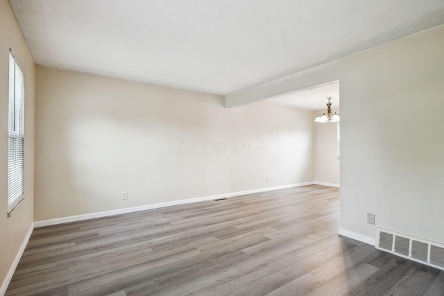 2117 Kilbourne Ave, Columbus, OH 43229 - spare room featuring wood finished floors, a chandelier, and baseboards