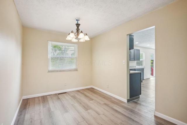 2117 Kilbourne Ave, Columbus, OH 43229 - empty room with plenty of natural light, light wood-type flooring, a chandelier, a textured ceiling, and baseboards