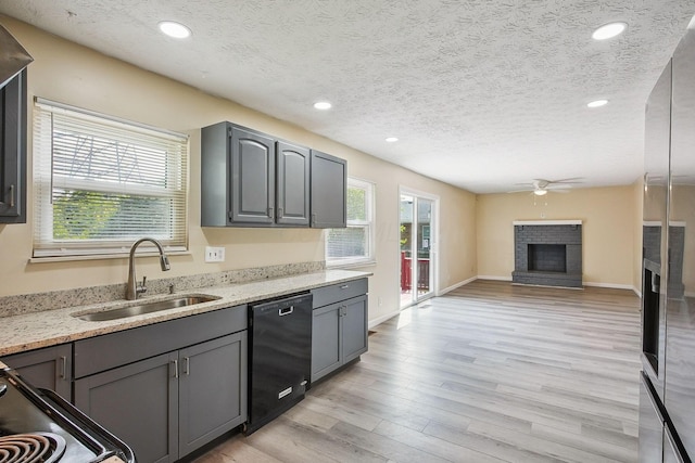 2117 Kilbourne Ave, Columbus, OH 43229 - kitchen featuring black dishwasher, a brick fireplace, a sink, ceiling fan, and a textured ceiling