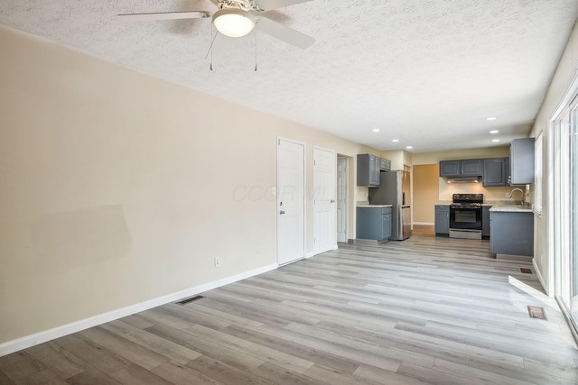 2117 Kilbourne Ave, Columbus, OH 43229 - unfurnished living room featuring a sink, ceiling fan, a textured ceiling, light wood-type flooring, and baseboards
