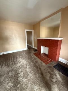 865 E Whittier St, Columbus, OH 43206 - unfurnished living room featuring baseboards, a fireplace, and carpet floors