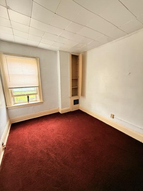869 E Whittier St, Columbus, OH 43206 - spare room featuring dark carpet, baseboards, and a paneled ceiling