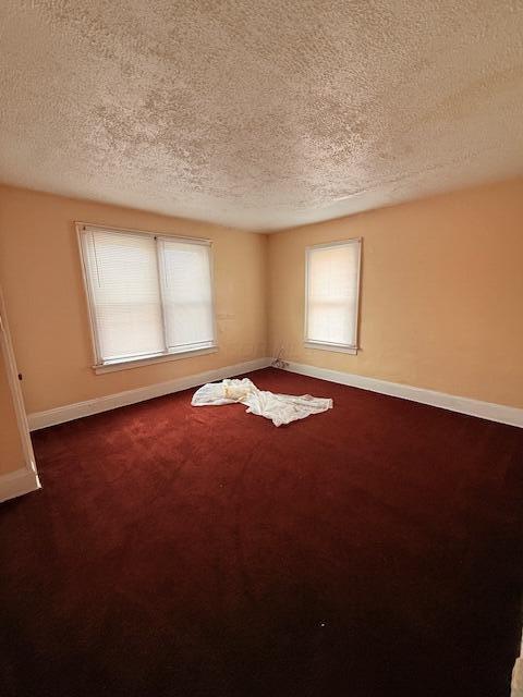 869 E Whittier St, Columbus, OH 43206 - empty room with a textured ceiling, baseboards, plenty of natural light, and dark colored carpet