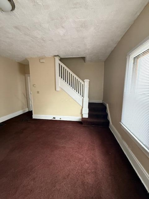 869 E Whittier St, Columbus, OH 43206 - unfurnished living room featuring a textured ceiling, stairway, carpet floors, and baseboards