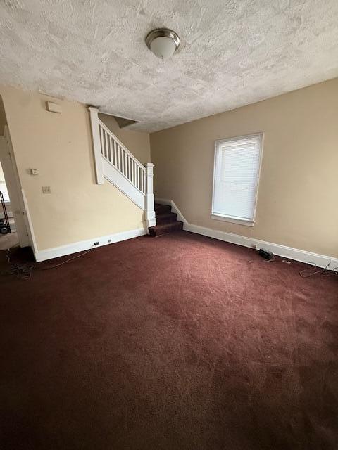 869 E Whittier St, Columbus, OH 43206 - unfurnished room with a textured ceiling, stairway, baseboards, and dark carpet