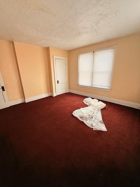 869 E Whittier St, Columbus, OH 43206 - unfurnished room with a textured ceiling, baseboards, and dark colored carpet