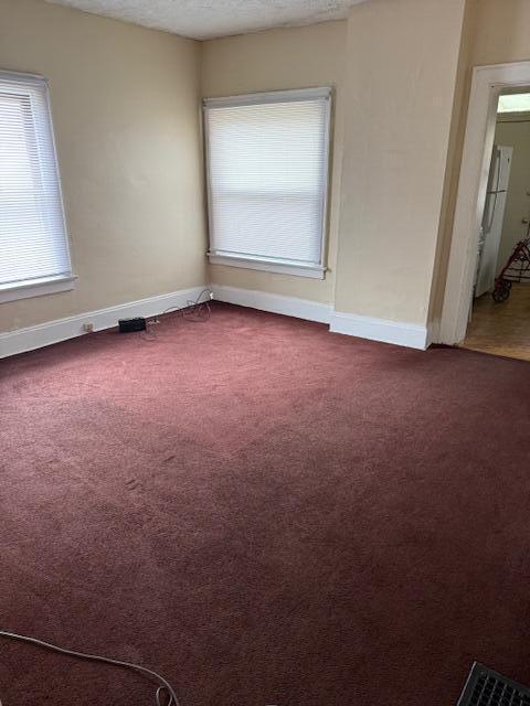 869 E Whittier St, Columbus, OH 43206 - empty room featuring dark carpet, healthy amount of natural light, baseboards, and a textured ceiling