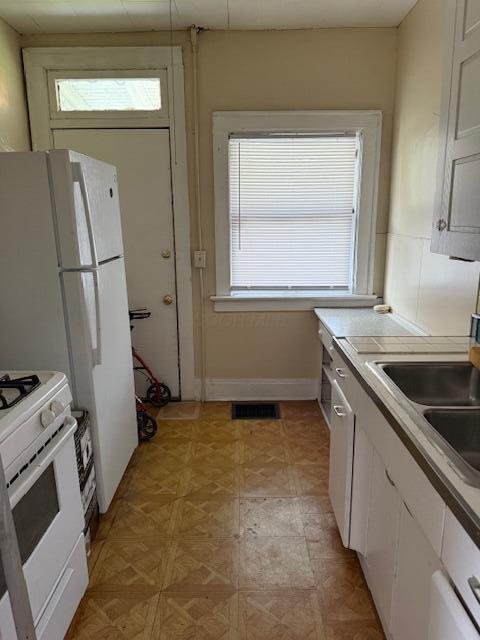 869 E Whittier St, Columbus, OH 43206 - kitchen featuring white range with gas cooktop, white cabinets, a sink, and light countertops