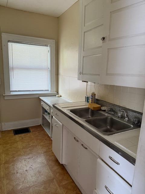 869 E Whittier St, Columbus, OH 43206 - kitchen featuring white cabinetry, a sink, tasteful backsplash, and baseboards