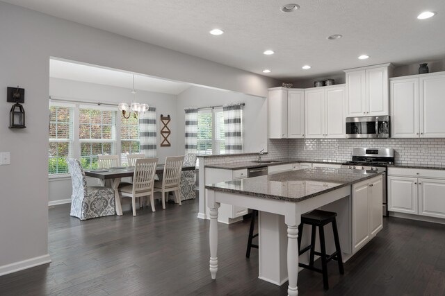 676 Ferguson Ave, Delaware, OH 43015 - kitchen with stainless steel appliances, a peninsula, tasteful backsplash, a chandelier, and white cabinetry