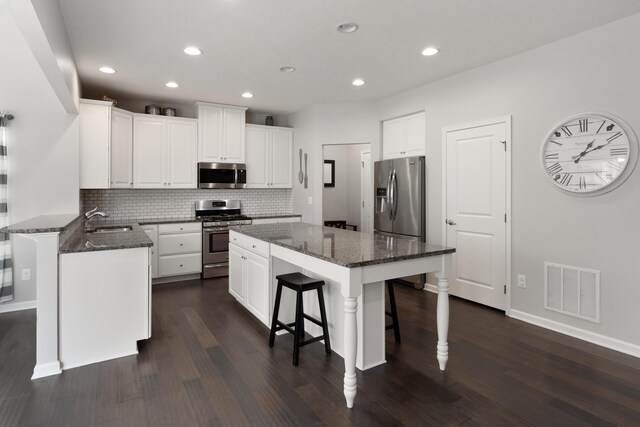 676 Ferguson Ave, Delaware, OH 43015 - kitchen featuring stainless steel appliances, a sink, a center island, a breakfast bar area, and dark wood-type flooring