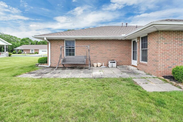 106 Kings Way W, Jefferson, OH 43162 - rear view of house featuring a patio area, a lawn, brick siding, and roof with shingles
