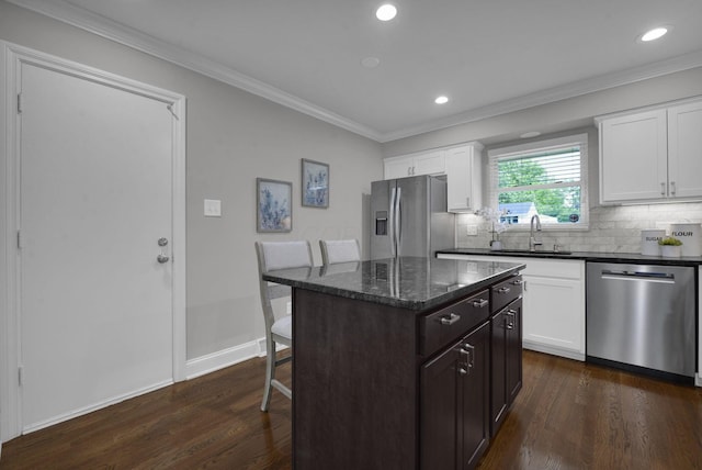 2608 Edgevale Rd, Columbus, OH 43221 - kitchen with appliances with stainless steel finishes, a breakfast bar area, dark wood finished floors, decorative backsplash, and ornamental molding