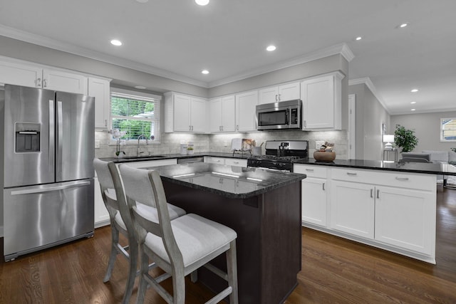 2608 Edgevale Rd, Columbus, OH 43221 - kitchen with stainless steel appliances, crown molding, dark wood-style flooring, white cabinetry, and a center island