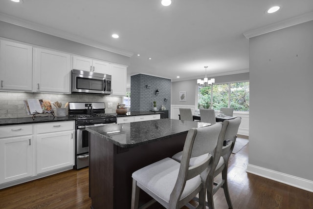 2608 Edgevale Rd, Columbus, OH 43221 - kitchen featuring appliances with stainless steel finishes, recessed lighting, white cabinetry, decorative backsplash, and a kitchen bar