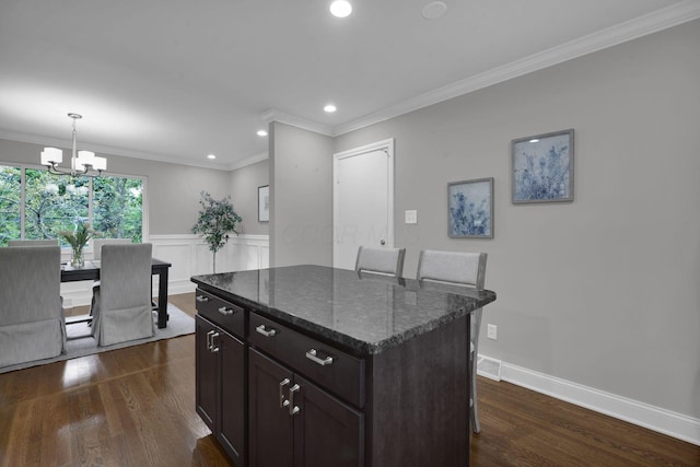 2608 Edgevale Rd, Columbus, OH 43221 - kitchen featuring dark wood-type flooring, a chandelier, a center island, ornamental molding, and a breakfast bar area