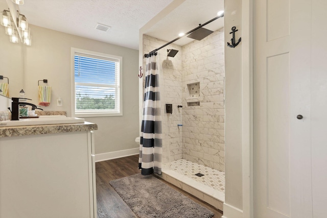 9559 Basil Rd NW, Baltimore, OH 43105 - full bathroom with vanity, tiled shower, wood finished floors, baseboards, and a textured ceiling