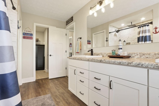 9559 Basil Rd NW, Baltimore, OH 43105 - full bath with vanity, wood finished floors, a tile shower, a textured ceiling, and baseboards