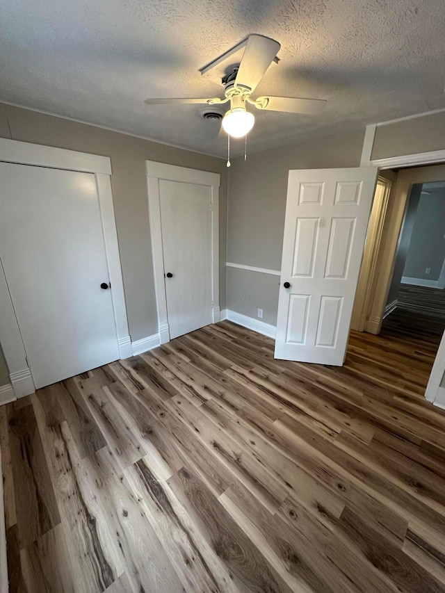 662 Frederick St, Lancaster, OH 43130 - unfurnished bedroom featuring wood finished floors, multiple closets, baseboards, a textured ceiling, and ceiling fan
