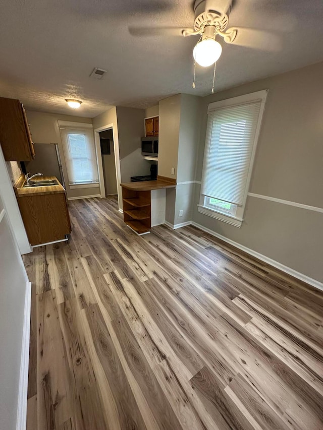 662 Frederick St, Lancaster, OH 43130 - kitchen featuring stainless steel microwave, brown cabinetry, a sink, wood finished floors, and baseboards