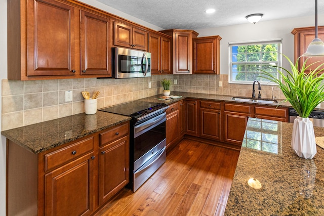 1245 Little Bear Loop, Lewis Center, OH 43035 - kitchen with stainless steel appliances, a sink, dark wood-style flooring, brown cabinets, and dark stone countertops