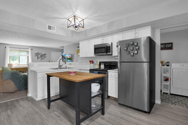 3195 Summerdale Ln, Columbus, OH 43221 - kitchen with stainless steel appliances, separate washer and dryer, a sink, wood counters, and light wood-style flooring