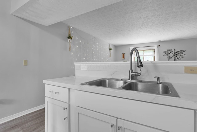 3195 Summerdale Ln, Columbus, OH 43221 - kitchen with a sink, a textured ceiling, wood finished floors, white cabinets, and light countertops