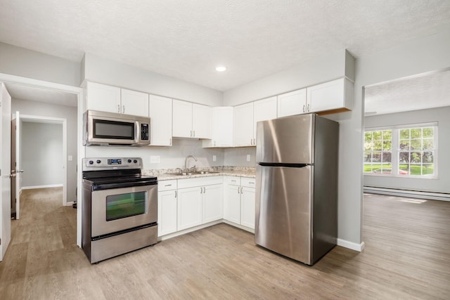 133 Blendon Rd, West Jefferson, OH 43162 - kitchen featuring appliances with stainless steel finishes, a sink, baseboard heating, light wood finished floors, and baseboards