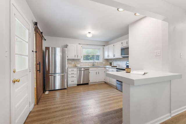 895 Caniff Rd, Columbus, OH 43221 - kitchen with appliances with stainless steel finishes, a sink, a peninsula, light countertops, and white cabinets