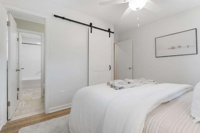 895 Caniff Rd, Columbus, OH 43221 - bedroom with a barn door, a closet, connected bathroom, baseboards, and a ceiling fan