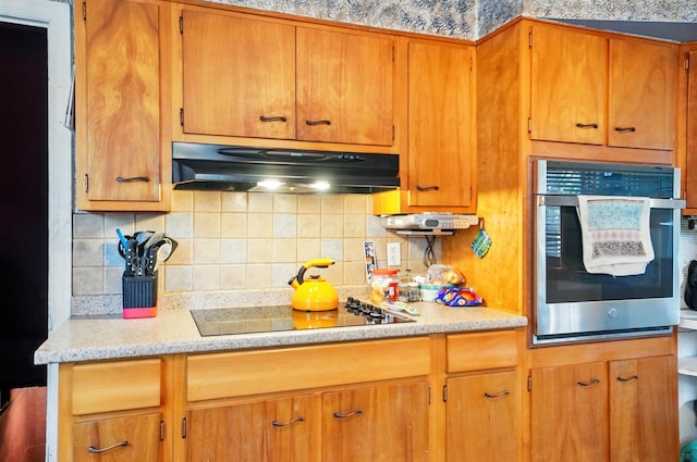 2506 Chester Rd, Columbus, OH 43231 - kitchen with under cabinet range hood, oven, light countertops, tasteful backsplash, and black electric cooktop