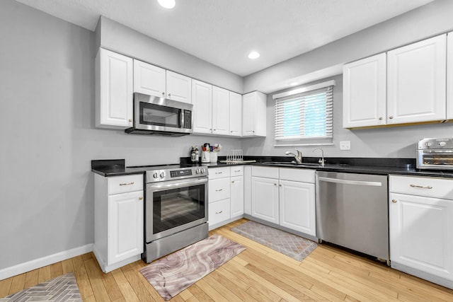 563 Wickham Way, Gahanna, OH 43230 - kitchen with stainless steel appliances, light wood-type flooring, white cabinets, dark countertops, and recessed lighting