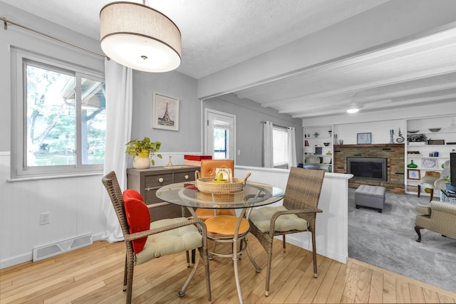 563 Wickham Way, Gahanna, OH 43230 - dining space with beam ceiling, hardwood / wood-style flooring, a ceiling fan, a fireplace, and a textured ceiling