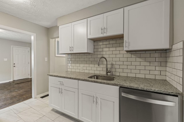 2592 Grasmere Ave, Columbus, OH 43211 - kitchen featuring dishwasher, a sink, white cabinets, a textured ceiling, and light stone counters