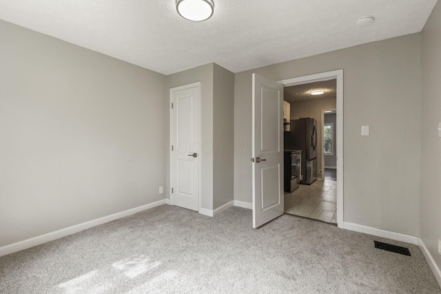 2592 Grasmere Ave, Columbus, OH 43211 - unfurnished bedroom with stainless steel fridge, baseboards, light colored carpet, and a textured ceiling