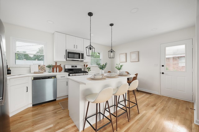 1079 Loring Rd, Columbus, OH 43224 - kitchen featuring appliances with stainless steel finishes, plenty of natural light, a kitchen bar, and light wood-style floors