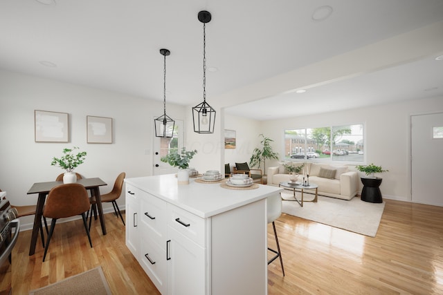 1079 Loring Rd, Columbus, OH 43224 - kitchen featuring a breakfast bar, light wood-style flooring, a kitchen island, white cabinetry, and hanging light fixtures